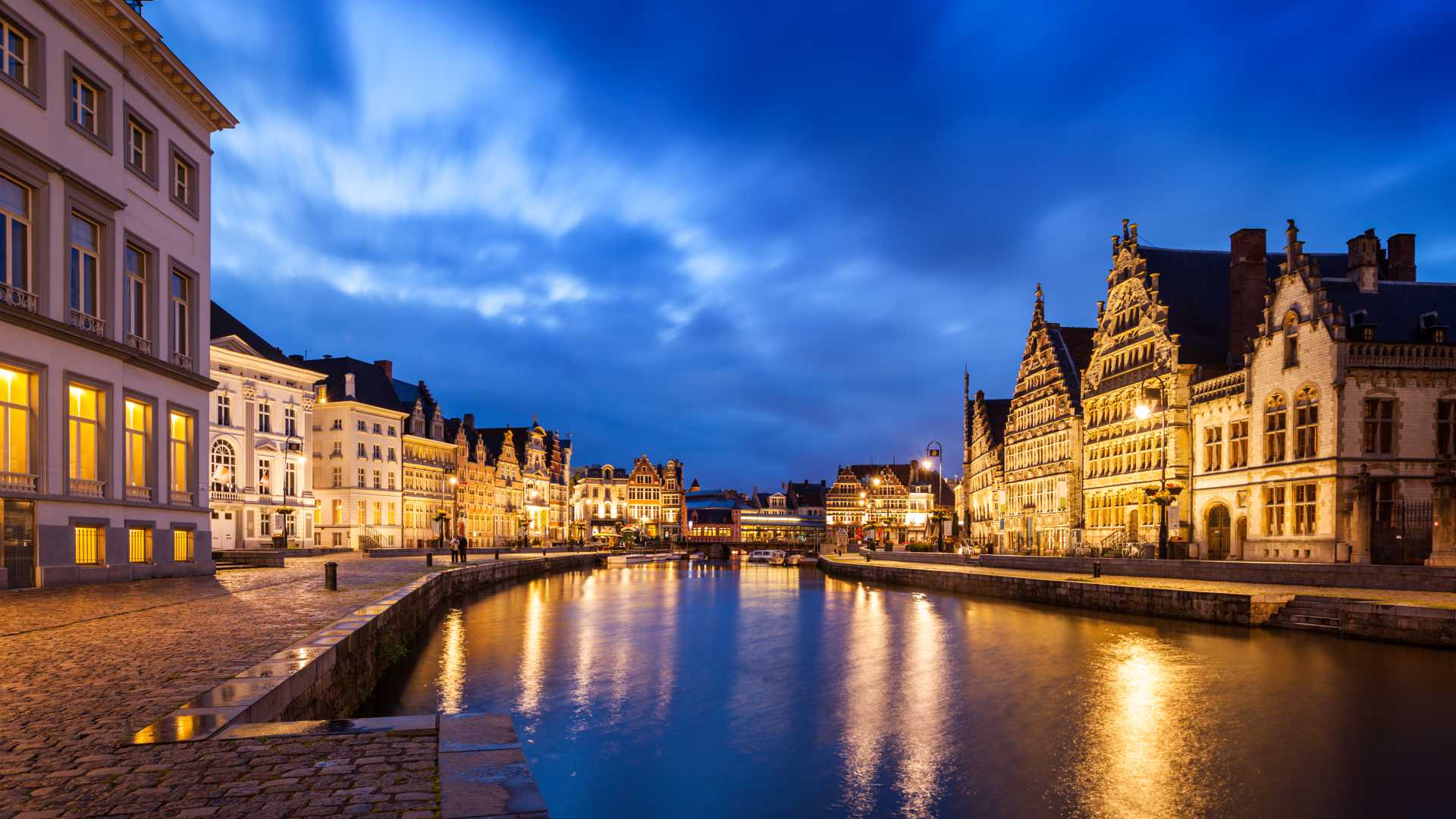 Die Straßen Graslei und Korenlei in Ghent leuchten im Abendlicht und spiegeln sich im ruhigen Kanal.