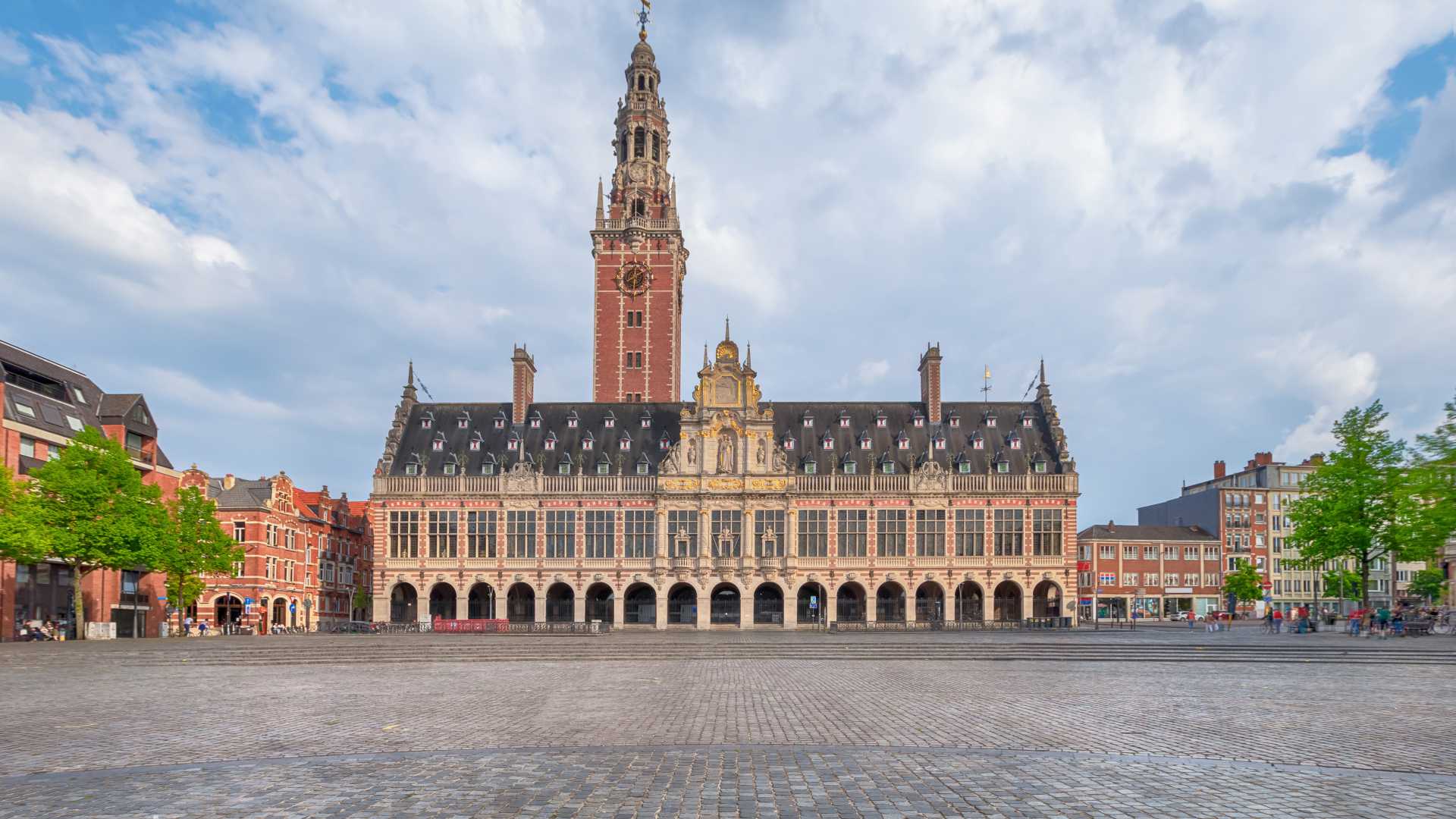 De grote universiteitsbibliotheek van Leuven staat majestueus op het Ladeuzeplein, onder een gedeeltelijk bewolkte hemel.