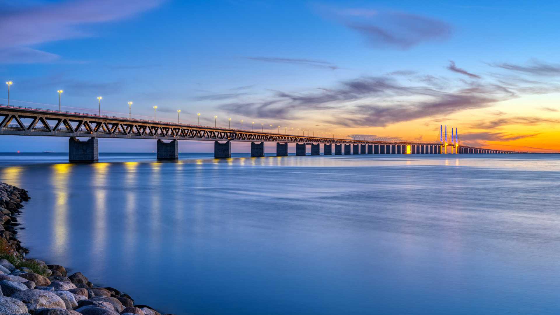 Le pont de l'Oresund s'étend sur des eaux calmes au crépuscule, reliant le Danemark et la Suède sous un ciel éclatant.