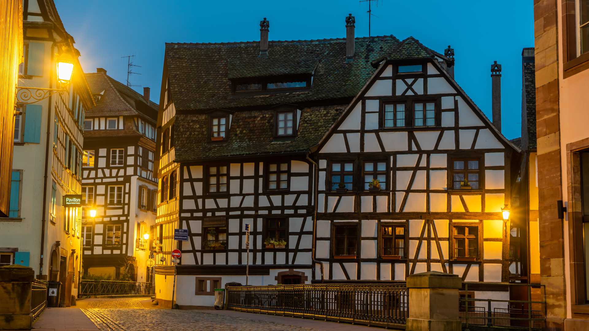 Fachwerkhäuser in Petite France, Straßburg, in der Abenddämmerung von Straßenlaternen beleuchtet.