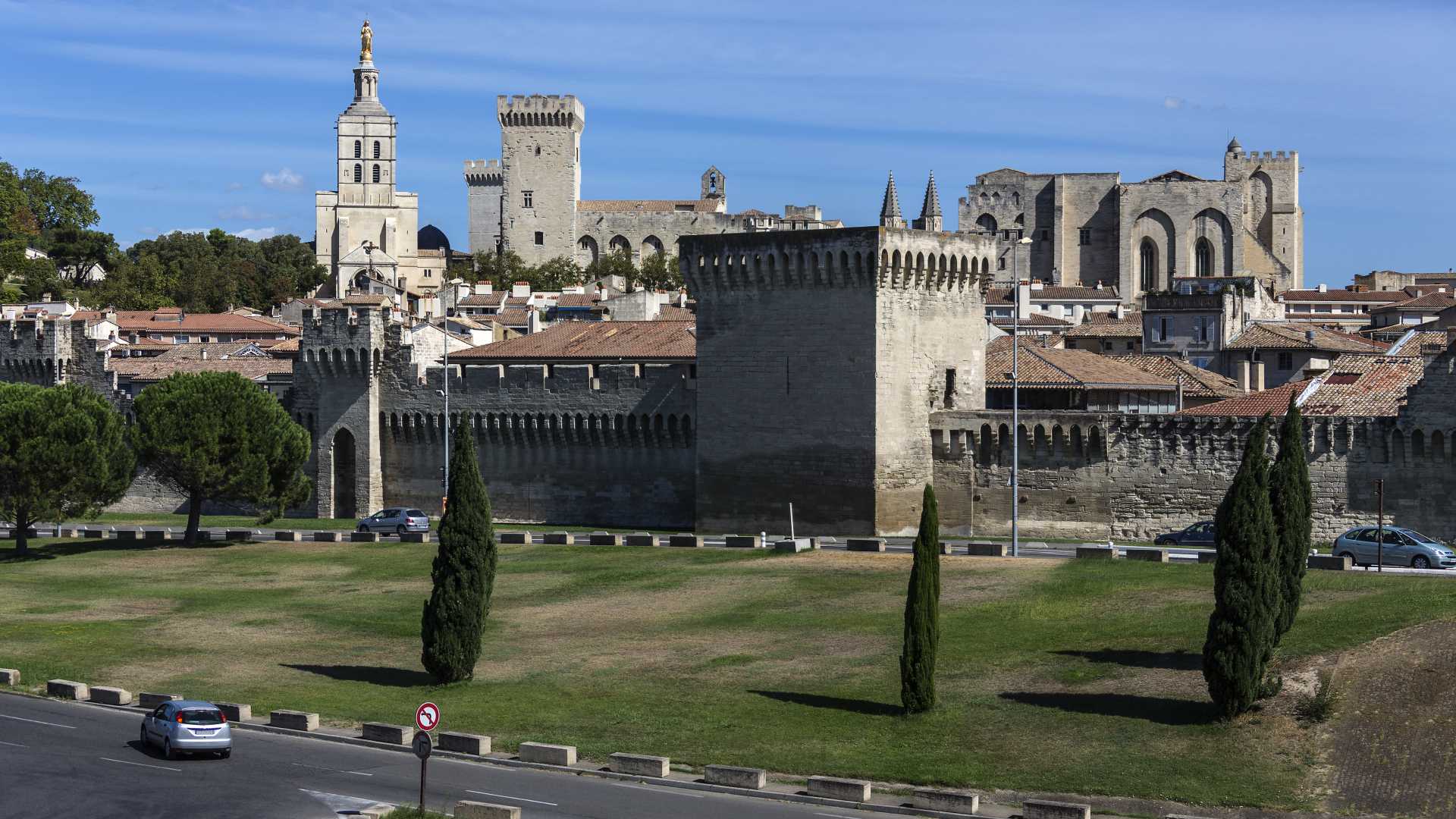 The skyline of Avignon, showcasing its ancient city walls and the Palais des Papes under a clear blue sky.