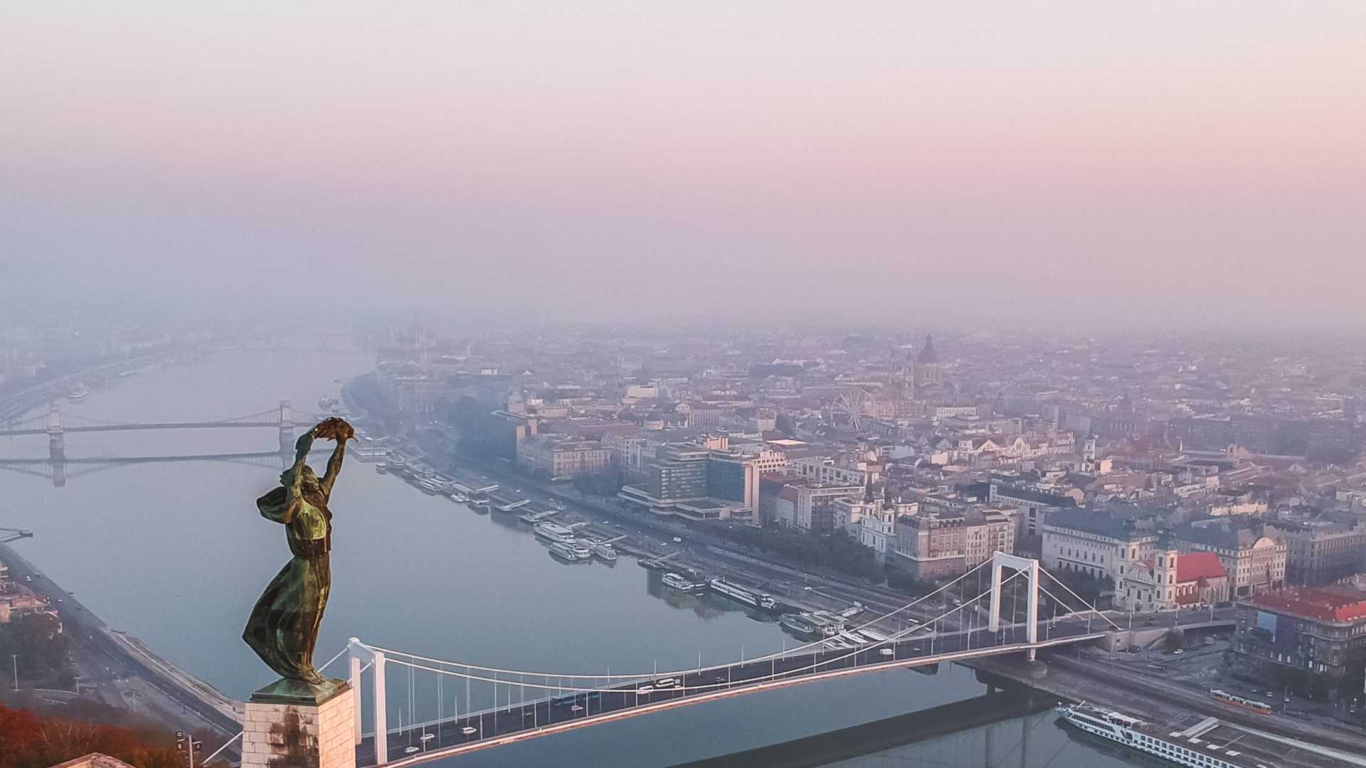 Luchtfoto van Boedapest bij zonsopgang, met het Vrijheidsbeeld, de Elisabethbrug en de Donau.