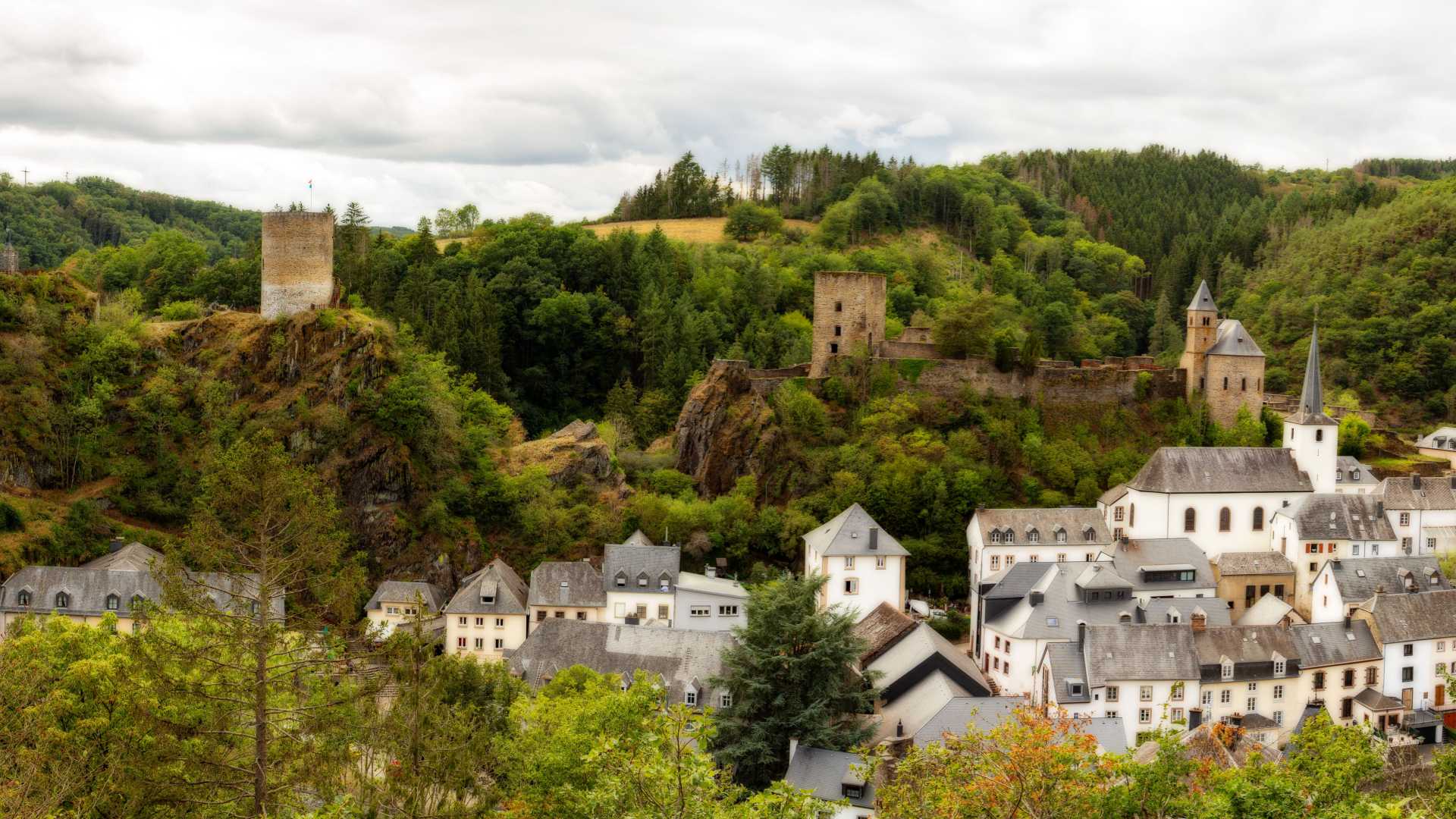 Ein malerischer Blick auf Esch-sur-Sûre mit seiner alten Burg und dem charmanten Dorf inmitten von üppigem Grün.