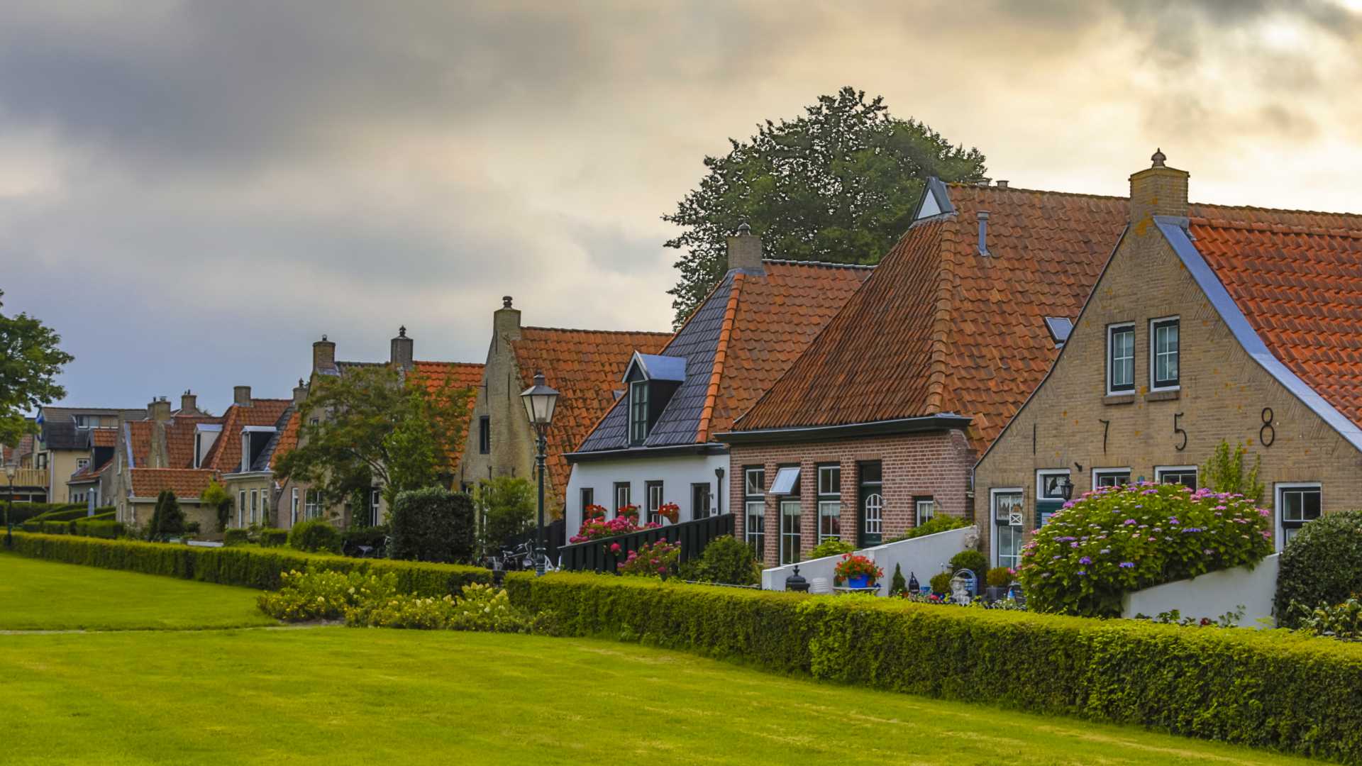 스히에르몬니코흐 마을의 붉은 기와지붕과 푸른 잔디가 있는 매력적인 네덜란드식 집들.