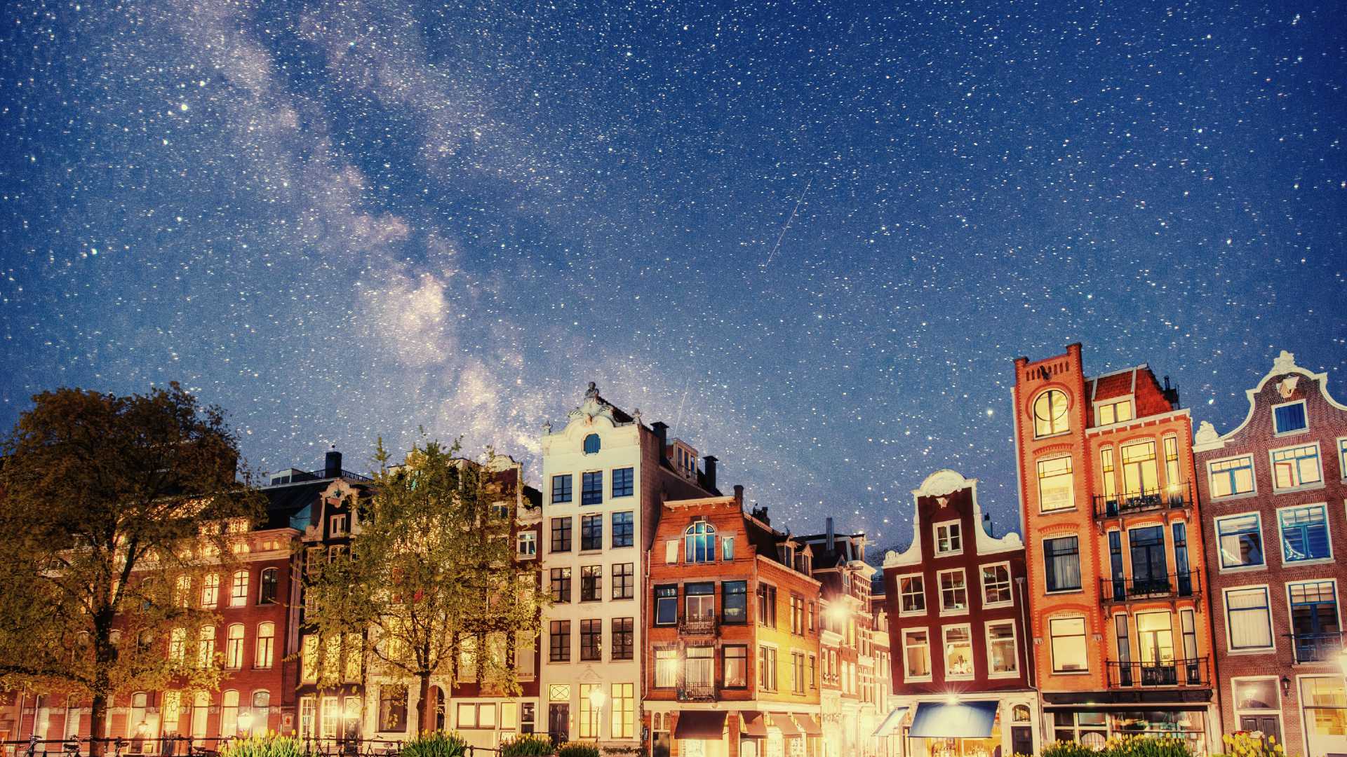 Amsterdam's iconic canal houses under a starry night sky, showcasing the city's serene beauty.