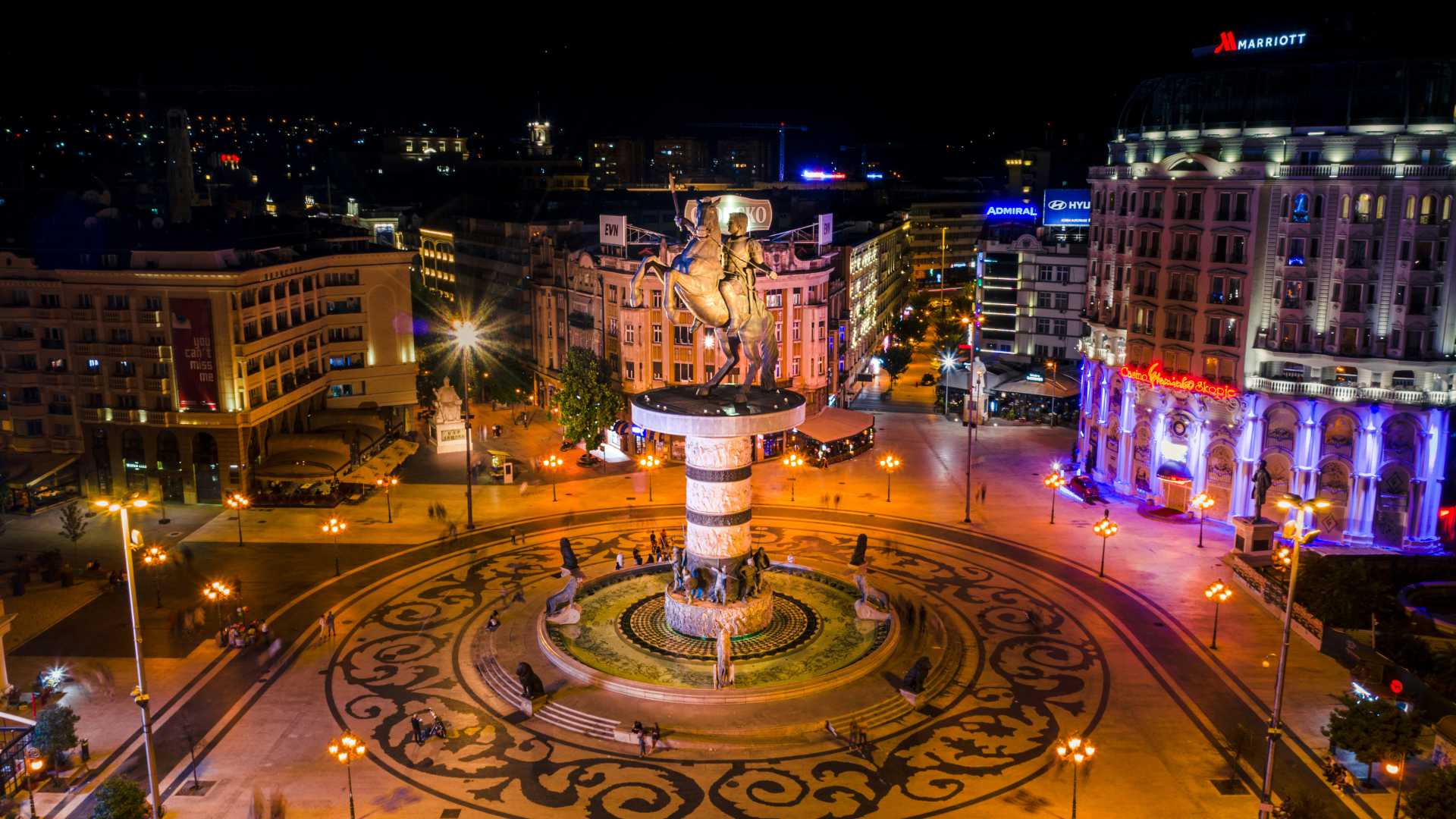 Vibrant night view of Macedonia Square in Skopje, featuring the grand Alexander the Great statue.