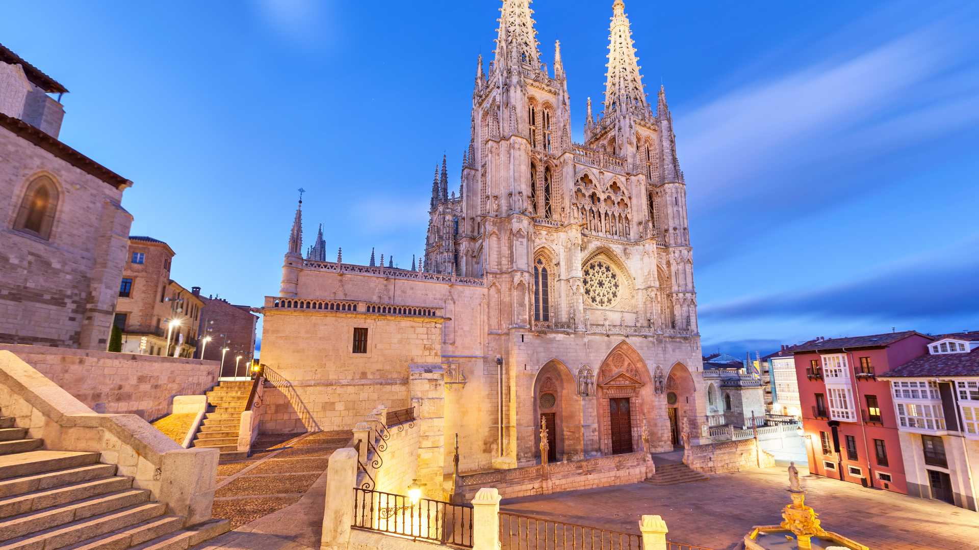 Majestic Burgos Cathedral illuminated at dusk, showcasing intricate Gothic architecture in a serene plaza.