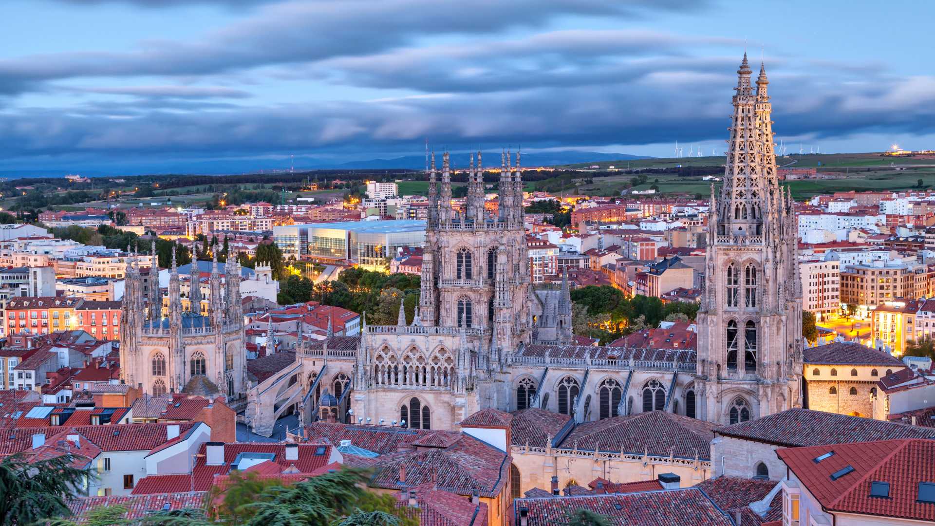 Burgos Cathedral overlooks the city as evening falls, with a dramatic sky adding to its Gothic splendor.