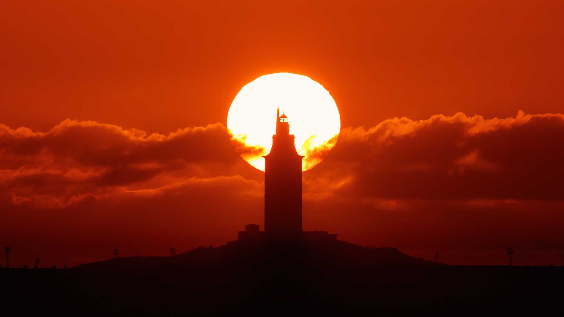 Silhouette de la Tour d'Hercule sur fond de coucher de soleil à La Corogne, en Espagne, avec des nuages spectaculaires.